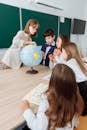 pexels photo 8926457 8926457 Teacher and students exploring geography with a globe in a classroom setting.